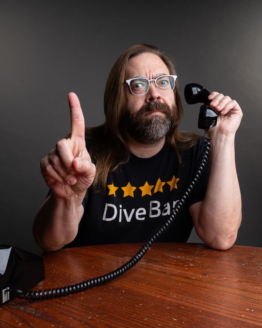 Gabriel Rutledge holding up a finger while answering an old rotary phone