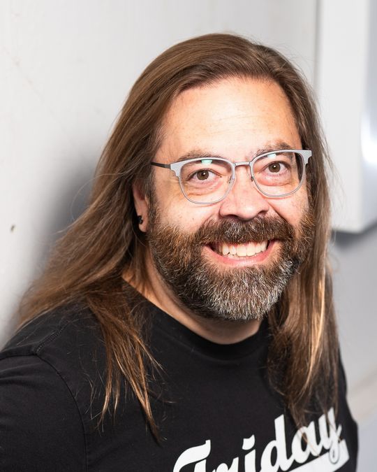 Gabriel Rutledge laughing, leaning against a white stairwell wall